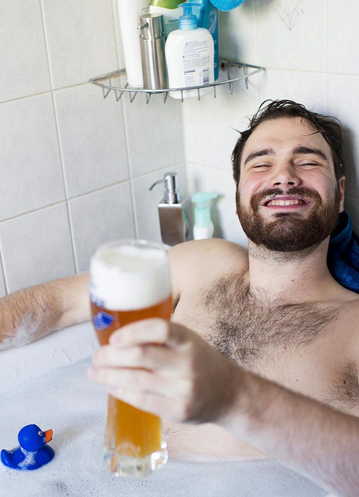Mann sitzt zufrieden mit Oettinger Bier in der Badewanne